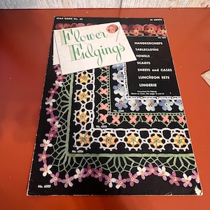 Könnte beinhalten: Ein vintage Star Book Nr. 65 Anleitungsheft mit dem Titel Flower Edgings und einer weißen Kartenauflage. Das schwarze Cover zeigt bunte Häkelmuster für Taschentücher, Tischdecken, Handtücher, Schals, Bettlaken, Bezüge und Wäsche.