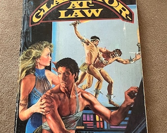 May include: A paperback book titled Gladiator-at-Law by Frederik Pohl and C.M. Kornbluth. The cover features a central illustration of a man and woman in the foreground, with two figures fighting in the background, all set against a dark blue backdrop.