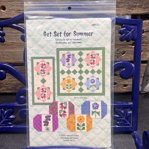 May include: A clear plastic package containing a quilting pattern titled "Get Set for Summer." The pattern includes designs for quilted placemats, a wall hanging, and a tablerunner. The design features floral motifs in various colors.