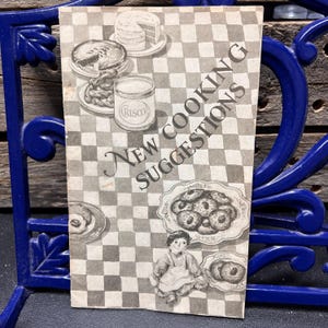 Puede incluir: Una taza de cerámica blanca con un asa negra y el texto "But First, Coffee" en negrita negra. La taza está sobre una superficie de madera. La taza mide aproximadamente 10 cm de alto.