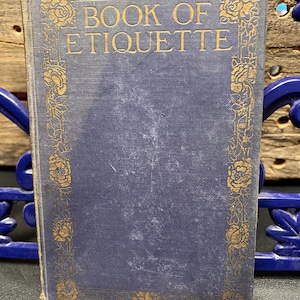 May include: A white ceramic mug with a black handle and the text "But First, Coffee" in a bold, black font. The mug is set against a blurred background, highlighting its simple design.