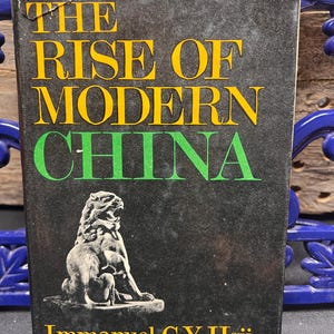 May include: A hardcover book titled "THE RISE OF MODERN CHINA" with yellow and green lettering on a black background. The cover features a detailed illustration of a stone lion and the author's name, Immanuel C.Y. Hsü.