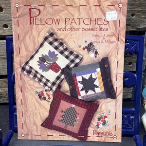 May include: A book cover titled "Pillow Patches and other possibilities" showing three pillow designs with floral, star, and Christmas tree patterns. The pillows are decorated with buttons. The cover is on a light brown background.