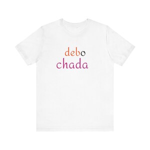 May include: White t-shirt with the text "debo chada" printed in orange, black, and pink.