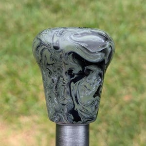 May include: A black and green marbled shift knob with a silver metal base.