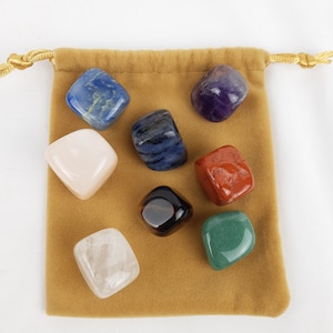 Peut inclure: Un ensemble de sept pierres roulées dans une pochette en velours marron. Les pierres sont de différentes couleurs, notamment bleu, violet, rose, rouge, marron et vert.