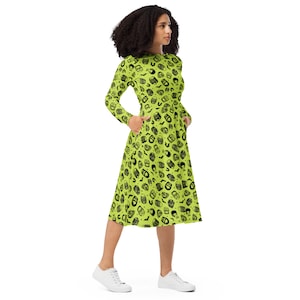 May include: A long-sleeved midi dress in a vibrant lime green, patterned with black skull and bat illustrations. The dress features a round neckline, pockets, and a flared skirt, suitable for Halloween or themed events.