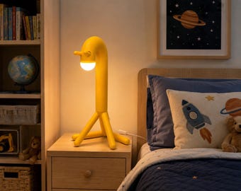 May include: A bright yellow table lamp with a long, curved neck and three legs, featuring a round, glowing white light bulb at the end of the neck. The lamp stands on a wooden nightstand next to a bed with a space-themed pillow and a teddy bear.