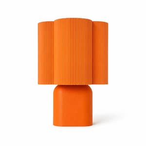 May include: A bright orange table lamp featuring a cylindrical base with a smooth matte finish and a wide, fluted lampshade with vertical ridges. The lamp has a uniform, vibrant orange color throughout its entire structure, creating a bold look.