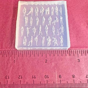 Op de afbeelding: Een doorzichtige siliconen mal met miniatuur menselijke figuren in verschillende poses. De vierkante mal meet ongeveer 6,35 cm breed. De gedetailleerde figuren zijn geschikt voor knutselprojecten.