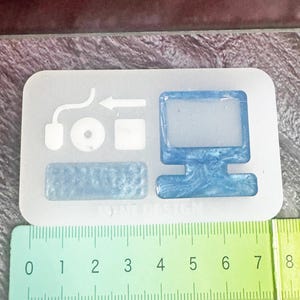 May include: A clear silicone mold with computer-themed shapes, including a monitor, keyboard, mouse, and other icons. The monitor and keyboard have a blue, swirled appearance. A ruler shows measurements up to 8 inches.