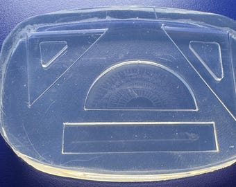 May include: A clear, oval-shaped silicone mold featuring geometric shapes for crafting. The mold includes two triangles, a protractor, and a rectangle, ideal for resin art or educational projects. The design is visible against a blue background.