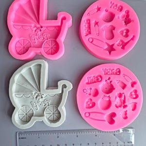 Puede incluir: Moldes de silicona rosas para manualidades con temática de bebé. Un molde presenta un cochecito con la palabra "Baby". Los otros moldes tienen formas relacionadas con bebés como un body, un imperdible y un biberón. Se incluye una regla.