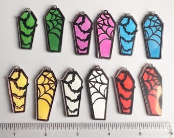 May include: A collection of coffin-shaped charms in various colors, including green, pink, blue, yellow, white, and red. Each charm features a spiderweb or bat design. The charms are approximately 1 inch in length, perfect for Halloween-themed crafts.