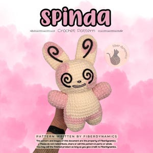May include: A crocheted Spinda plushie with a cream and pink color scheme. The plushie has large, swirly eyes and ear markings, and the text "Spinda Crochet Pattern" is above it. The image also includes the FiberDynamics logo and text.