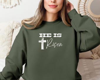 May include: A green sweatshirt with the text "He is Risen" and a white cross graphic.