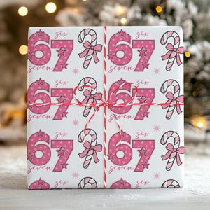 May include: A wrapped present with pink patterned wrapping paper. The paper features the numbers 67, the words "six" and "seven", candy canes, and stars. The gift is tied with red and white twine.