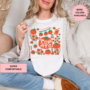 May include: White t-shirt with a graphic of red tomatoes, green leaves, and the text "TOMATOES" and "TOMATO".