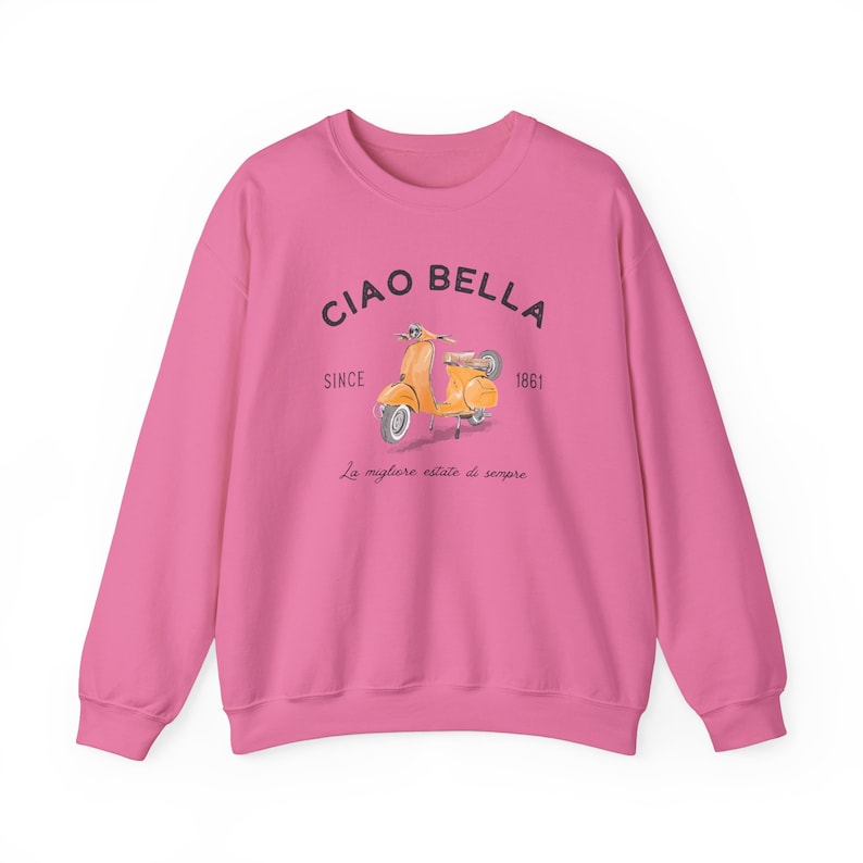 K&ouml;nnte beinhalten: Rosafarbener Pullover mit einem Aufdruck eines gelben Rollers und dem Text "Ciao Bella" mit den Worten "Since 1861" und "La migliore estate di sempre" darunter.