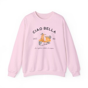 K&ouml;nnte beinhalten: Ein rosa Sweatshirt mit einem grafischen Aufdruck eines gelben Rollers und dem Text "Ciao Bella" in Schwarz. Die Texte "Since 1861" und "La migliore estate di sempre" sind ebenfalls in Schwarz gedruckt.