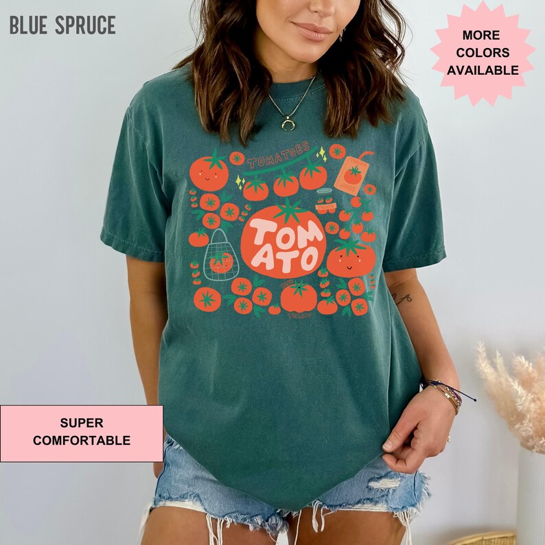 May include: A teal blue t-shirt with a graphic of tomatoes and the text "TOMATO" in a white box. The graphic also includes a red juice box and the text "TOMATOES".