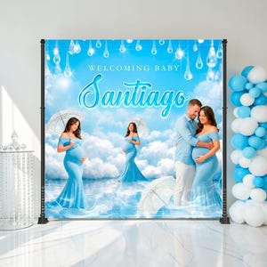 May include: A backdrop for a baby shower with a blue sky and cloud design. The words "Welcoming Baby Santiago" are displayed. The backdrop features images of a pregnant person in a blue dress and a couple embracing.