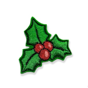 May include: A green holly leaf with three red berries. The holly leaf is embroidered with a green thread and the berries are embroidered with a red thread.