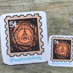 May include: Two brown and white postage stamp stickers with a black and white image of a triangle with an eye inside. The image is surrounded by a circle with a question mark and other symbols. The text "5¢" is printed on each sticker. The text "@sapphiresop_handmade" is printed on the bottom of each sticker.