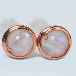 May include: A pair of copper wire wrapped earrings with iridescent moonstone cabochons.