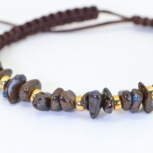 May include: A brown macrame bracelet with dark brown, irregularly shaped stones and small gold-coloured beads. The bracelet has an adjustable fastening.
