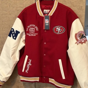 May include: A red and cream varsity jacket featuring San Francisco 49ers branding. The front displays the team logo, the text Faithful, and National Football League patches. The sleeves are cream with a blue N patch and a circular team emblem.