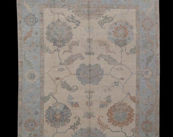 May include: A beige rug with a light blue border and a floral pattern in shades of blue, brown, and beige.