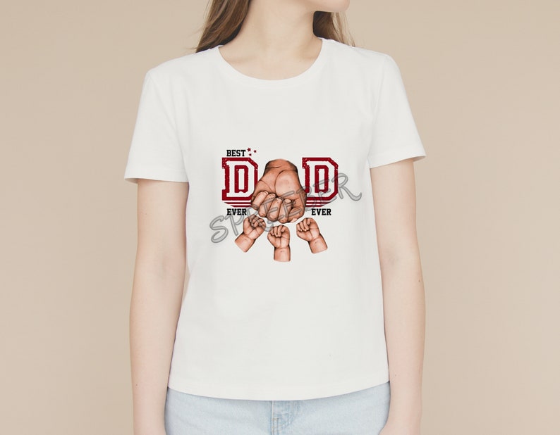 May include: White t-shirt with a red graphic that says "Best Dad Ever" with a fist and smaller hands around it.
