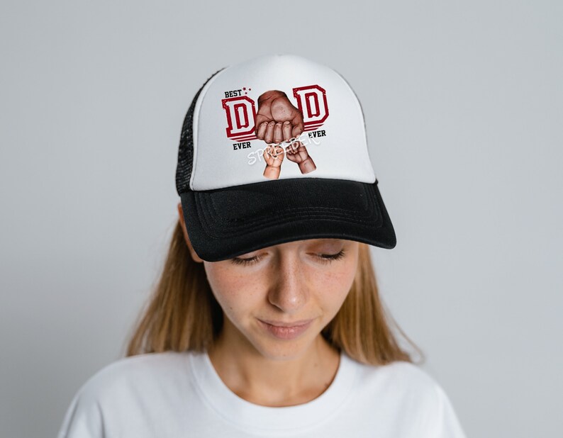 May include: A black and white trucker hat with a red and white graphic that says "Best Dad Ever" with a hand holding a smaller hand.