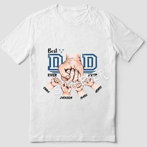May include: White t-shirt with a blue and white graphic that says "Best Dad Ever" with a hand holding the hands of five children. The children's names are Emma, Jackson, Max, Henry, and a fifth name that is unclear.
