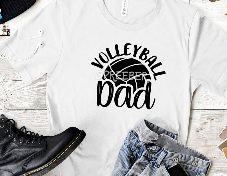 May include: White t-shirt with black text that reads "Volleyball Dad" and a volleyball graphic.