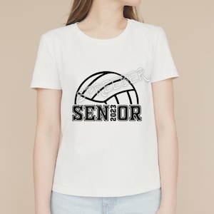 May include: White t-shirt with a black volleyball graphic and the text "SENIOR 2023"