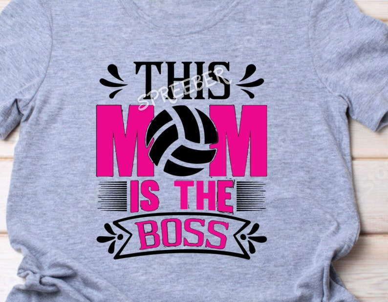 May include: Gray t-shirt with the text "This Mom is the Boss" in black and pink. A volleyball graphic is in the center of the text.