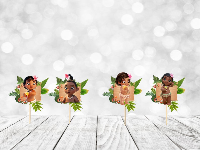 May include: Four cupcake toppers featuring a cartoon baby with brown skin, brown hair, and a flower in their hair. Each topper is set against a green leafy background with a brown sign.