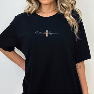 May include: Black t-shirt with the embroidered text "Full of Happiness" in a colorful, floral design. The shirt is a classic crew neck style, made of soft material.