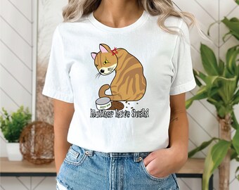 May include: White t-shirt featuring a cartoon cat with brown and tan stripes, an angry expression, and a red mark above its eye. The cat sits near a spilled food bowl. Text reads "Rather have Sushi."