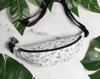 May include: A white fanny pack with a black adjustable strap. The fanny pack has a black zipper and a white and black print of cacti and other desert plants.