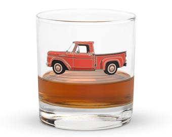 May include: A red pickup truck sits inside a clear glass filled with amber liquid. The truck is a vintage model with a white cab and a black bed.
