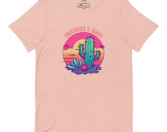 May include: A pink heather t-shirt with a graphic of a cactus in a desert sunset. The text "Sunshine & Cacti" is above the graphic.