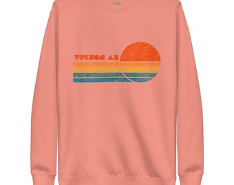 May include: A peach-colored sweatshirt with a vintage-style graphic of a sunset over the text "Tucson AZ".