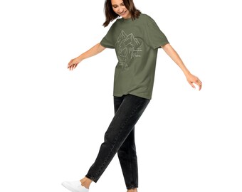 May include: A woman wearing a green t-shirt with a white graphic of mountains and the text "Mountain Mama". She is wearing black jeans and white sneakers.