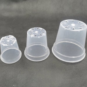 May include: Three clear plastic plant pots. Each pot has a flared rim and drainage holes at the base. The pots are made of a translucent material. The pots are of different sizes, suitable for various plants. The pots are made in China.