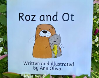 Puede incluir: Una portada de libro blanca con el título "Roz y Ot" en texto negro. La portada presenta una ilustración de dibujos animados de dos nutrias, una marrón y otra gris, con la nutria gris sosteniendo un pez. El texto "Escrito e ilustrado por Ann Oliva" está debajo de la ilustración.