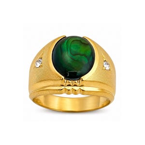 Pode incluir: Um anel dourado com uma grande pedra verde redonda com padrões em espiral. O anel tem uma banda texturizada e duas pequenas pedras claras em cada lado da pedra central. Uma peça de joalharia ousada e clássica.
