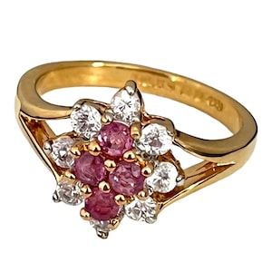 Pode incluir: Um anel de ouro com um grupo de safiras cor-de-rosa e diamantes brancos engastados em forma de flor.